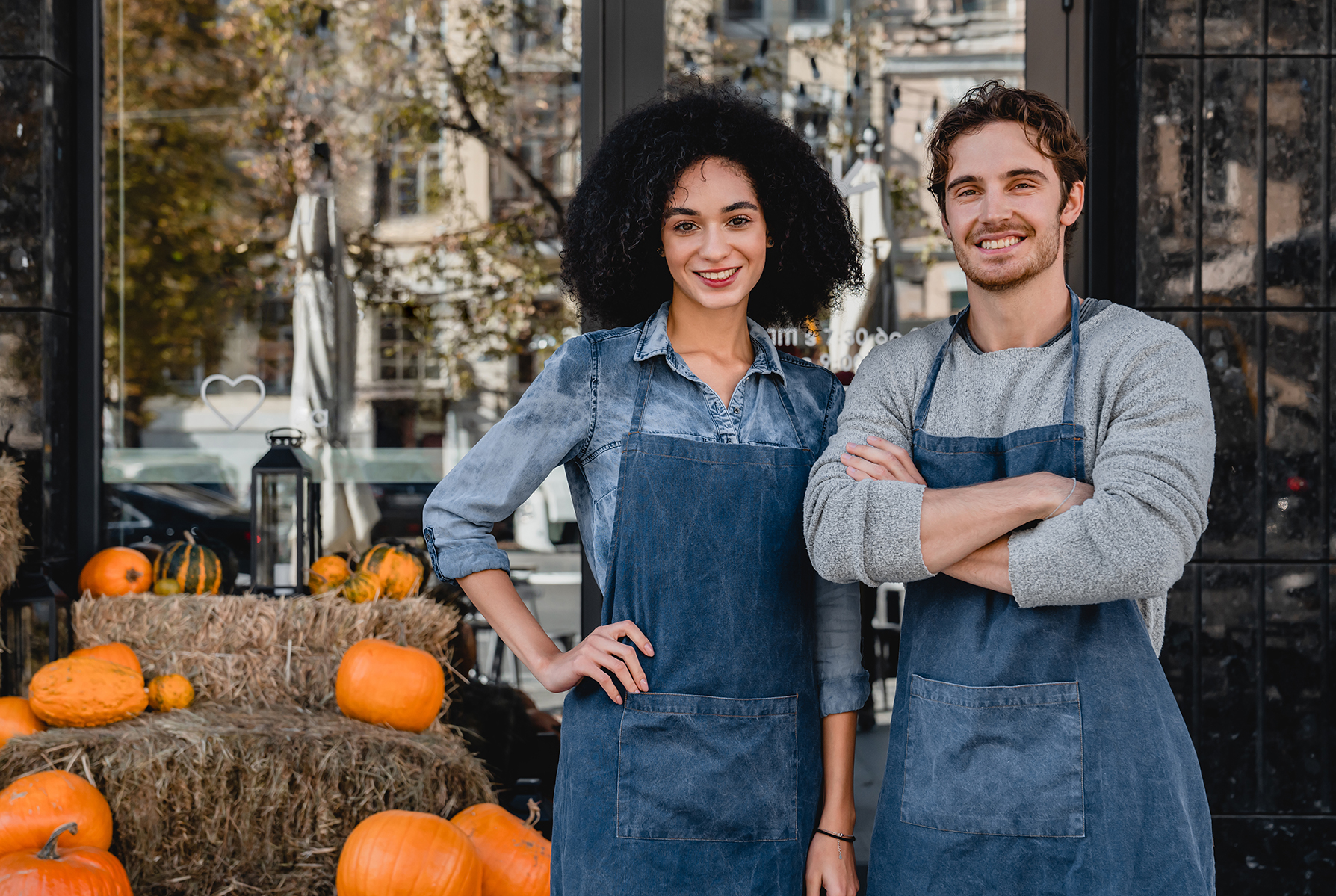 Portrait of young man and woman cafe owners standing outdoor front of their cafe